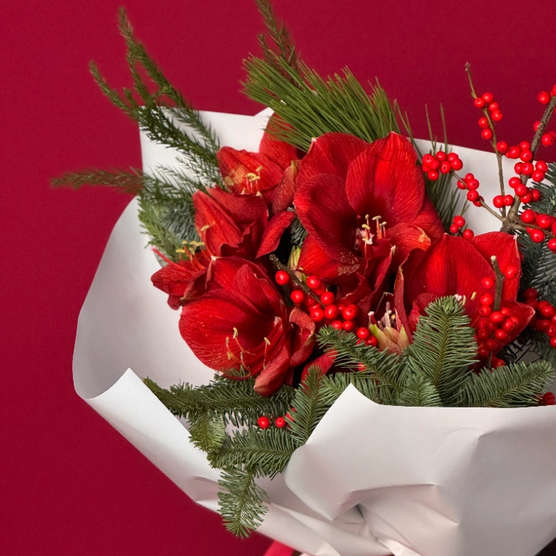 Яркий букет с алыми амариллисами и хвоей